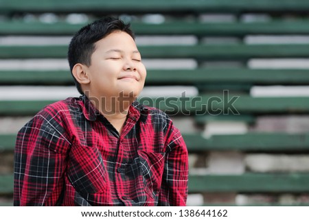 an asian boy smiling with eyes closed shows a happiness expression