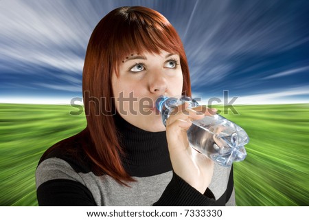 Beautiful girl with red hair drinking water, thirsty. Studio shot.