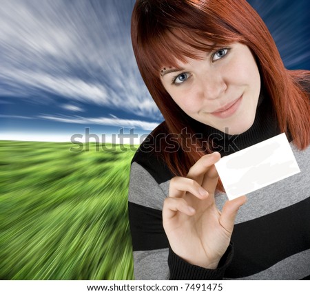 Smiling successful girl with red hair holding a blank empty business or greeting card. Studio shot.