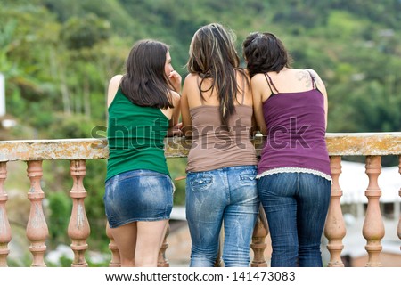 Three young ladies sight seeing with their backs to the camera, green in distance