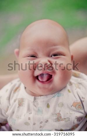 Beautiful expressive adorable happy cute laughing smiling baby infant face showing tongue