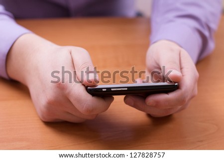 Businessman writes a message and looking for contacts on your mobile phone