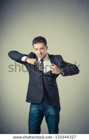 business man tearing off his shirt on gray background