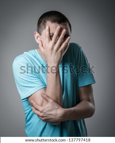man covered his face with his hands on a gray background