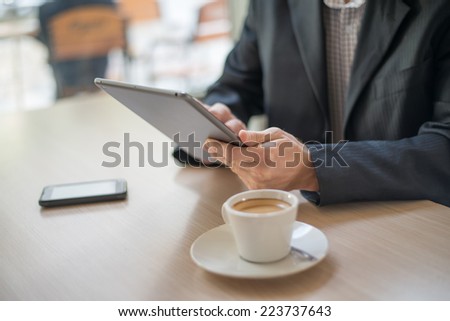 Man with tablet computer reading news at motning in cafe
