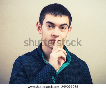 Young casual male shows silence please gesture