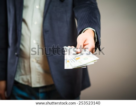 Business executive in formal suit giving money as a bribe