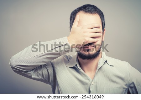 Portrait of a handsome man covering his eyes with hand