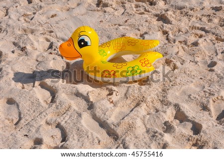 Inflatable toy. An inflatable duck on beach sand.