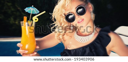 beautiful, suntanned, young woman drinking cocktail, and enjoys in the summer afternoon near the pool. Photo toned in color style instagram filters