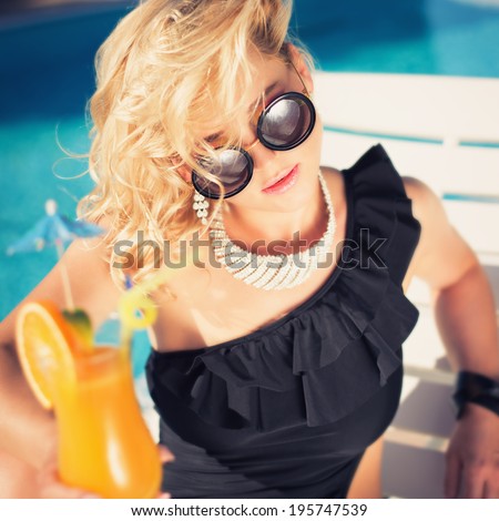 beautiful, suntanned, young sexy woman drinking cocktail, and enjoys in the summer afternoon near the pool. Photo toned instagram filters style