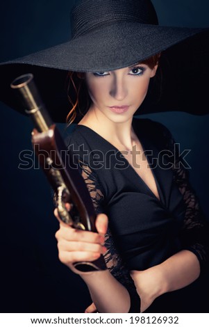 girl pirate with ancient pistol in hand on a black background. Vogue style