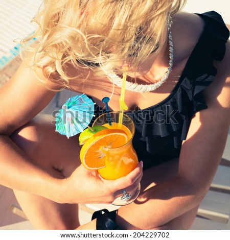 beautiful, suntanned, young sexy woman drinking cocktail, and enjoys in the summer afternoon near the pool. Photo with instagram style filters