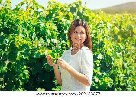 beautiful young woman, walks on a vineyard in a hot summer, sunny day