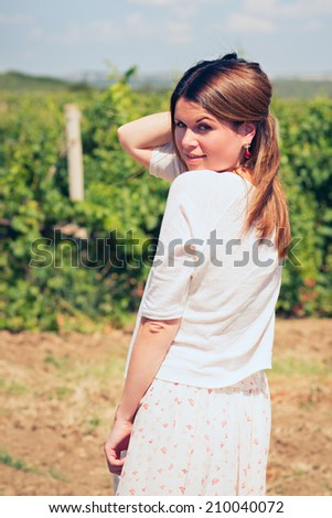 beautiful young woman, walks on a vineyard in a hot summer, sunny day.