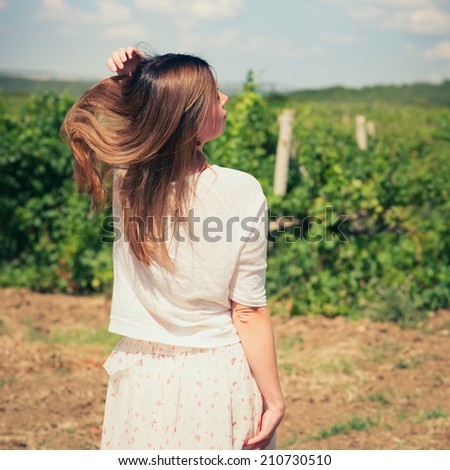 beautiful young woman, walks on a vineyard in a hot summer, sunny day. Photo with instagram style filters