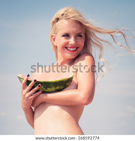young beautiful girl, attractive blonde, enjoys tropical weather, eats a water-melon, wind develops beautiful long hair. Photo with instagram style filters