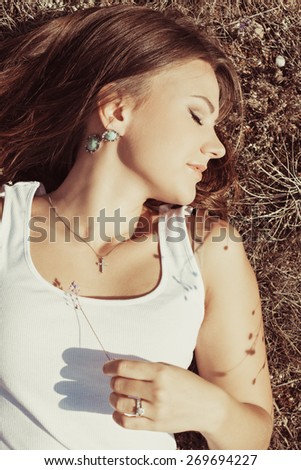 Beautiful young woman lying on the grass enjoying summer sun. girl in a long skirt and with long hair poses in warm spring day