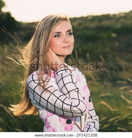 portrait of the attractive, slender, beautiful young Caucasian  blonde girl outdoor. Beautiful modern woman  with the long developing fair hair in a loose dress. dressy style. snub nose. instagram