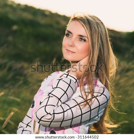 portrait of the attractive, slender, beautiful young Caucasian  blonde girl outdoor. Beautiful modern woman  with the long developing fair hair in a loose dress. dressy style. snub nose. instagram