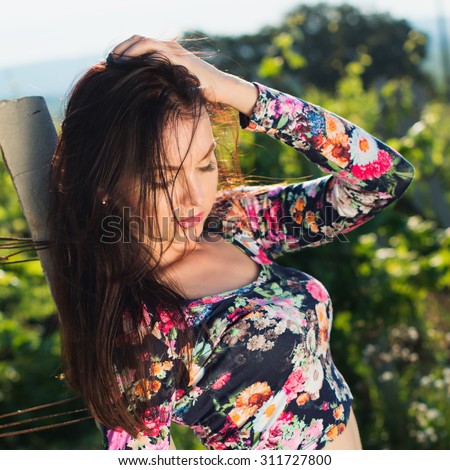 Sexy beautiful brunette woman with slim tanned body, long developing hair, clean face posing outdoor enjoys fine warm summer weather. instagram style
