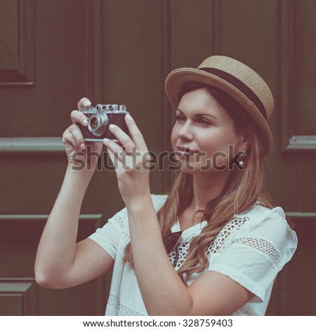 young attractive woman in hat, white dress and retro camera poses against Paris. Fashion and city style. Photo with instagram style filters