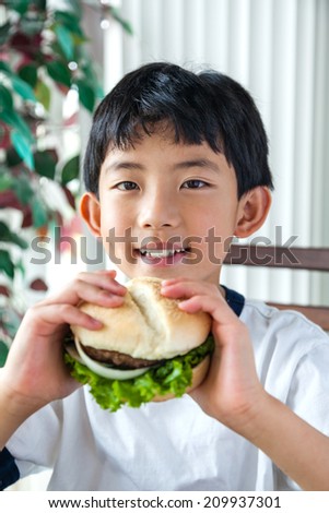 Asian boy having a burger for lunch.