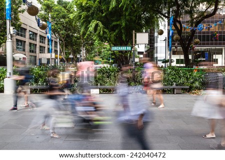 Deliberate motion blur on the crowd along Singapore\'s Orchard Road, a 2.2 km-long boulevard that is famous for its shopping and entertainment enclave. A road sign in the middle reads \