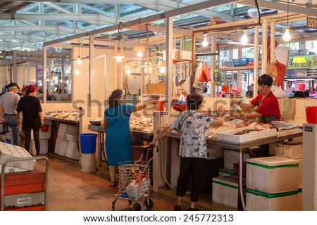 SINGAPORE - DECEMBER 11: A fishmonger at a local wet market in Singapore helping a customer Dec. 11, 2014. For local residents, a wet market is the place to buy groceries and the freshest produce.
