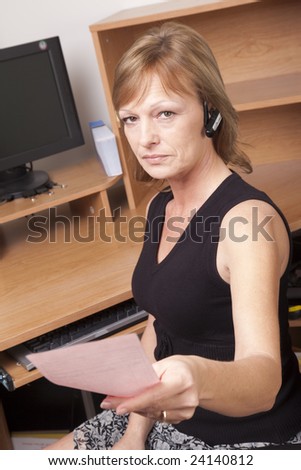 A female business woman giving a pink slip while seated at her desk.