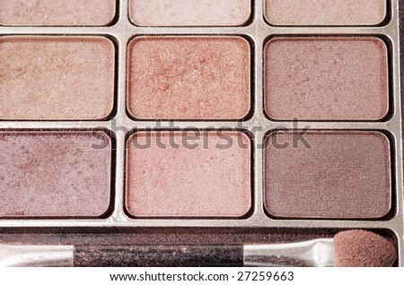 Multiple shades of eye shadow with a brush and loose powder flakes