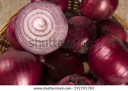 A close-up of red onions in a basket over a table.
