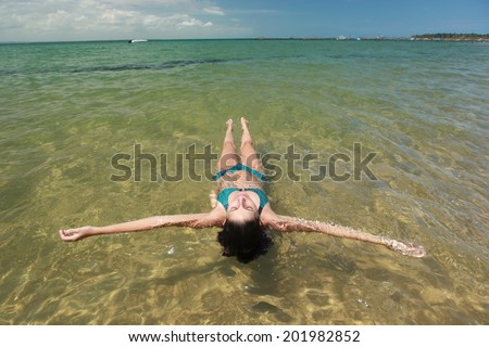 A woman floating on clean water at the beach. Barra Grande, Bahia - Brazil
