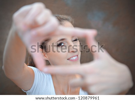 Portrait of young woman creates a frame with her hands