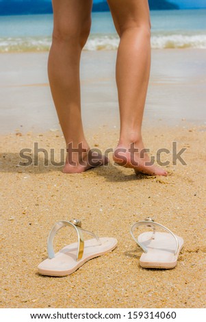 shoes and woman leg on sand beach