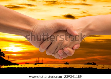 Business man and woman make hand shake with beautiful sunset sky.