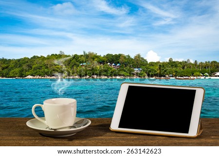 Hot coffee with tablet PC on table. With beautiful sea and island background.