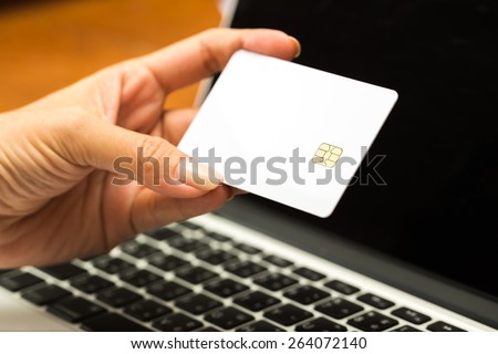 Business and finance concept. Hand hold blank credit cards with notebook PC background.