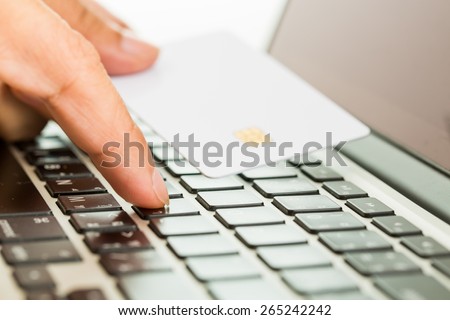 Hands entering credit card information into a laptop. Online shopping concept.