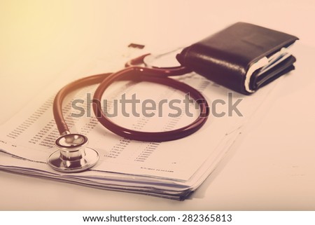 Medical expense concept. Stethoscope on record list with old wallet. Vintage filter.