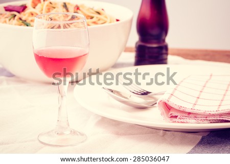 Dinner set with spaghetti. Focus on wine glass. Vintage filter.