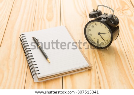 Book and pen with alarm clock. Office hour time concept.