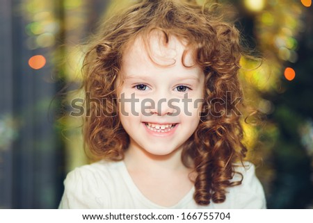 Beautiful little baby girl looking at the camera and smiles on the background of of the Christmas tree