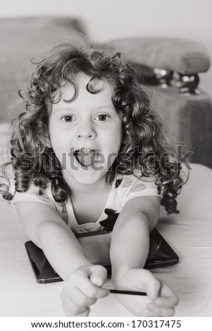 Black and white photo of a curly girl playing in the tablet PC.