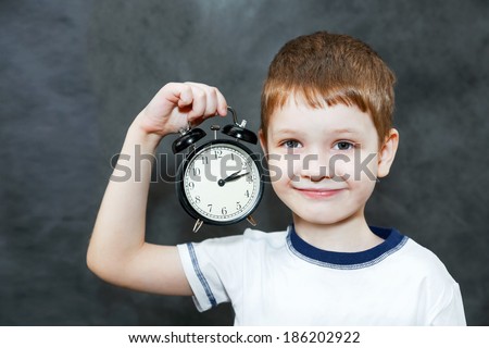 Little boy holding alarm clock.