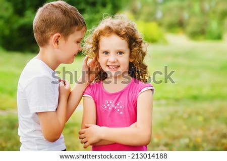 The little boy whispers a secret on an ear to the girl.