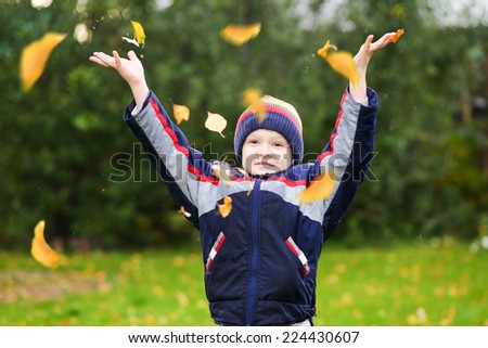 Happy boy throws the autumn leaves in the air.