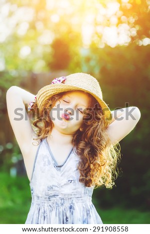 Funny little girl in a straw hat, shaped his lips for a kiss.