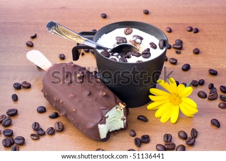 Food & Drinks - Desserts - Cup with vanilla ice cream and bitten ice cream bar on wood table, decorated with coffee grains and yellow daisy.