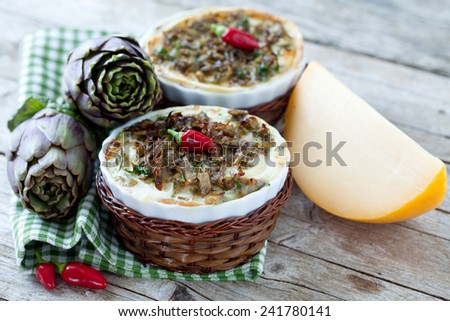 Flans made with artichokes, spinach, cheese and ground meat, decorated with red chili peppers.